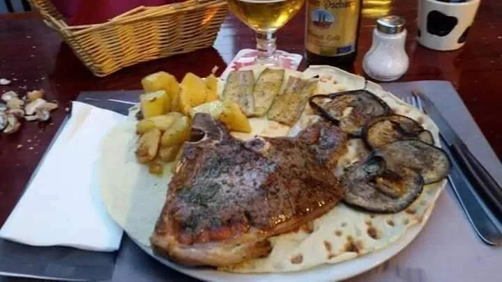 Una bistecca alla piastra servita sul pane carasau con patate arrosto, zucchine e melanzane grigliate