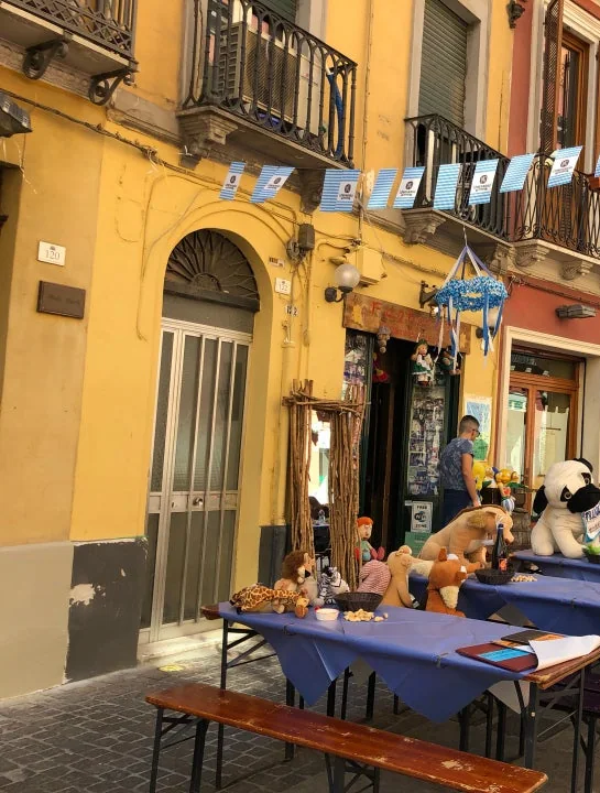 L'ingresso del Foghorn's sul Corso Vittorio Emanuele: facciata gialla, bandierine bavaresi tese fra i balconi e tavoli con tovaglie blu davanti alla porta